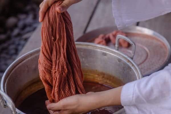 a dyed piece of fabric coming out of a dye bath