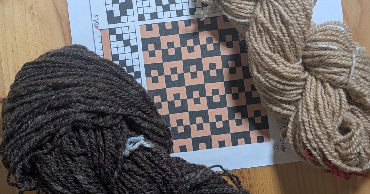 a weaving draft and 2 skeins of yarn in light and dark showing the plan for weaving cloth