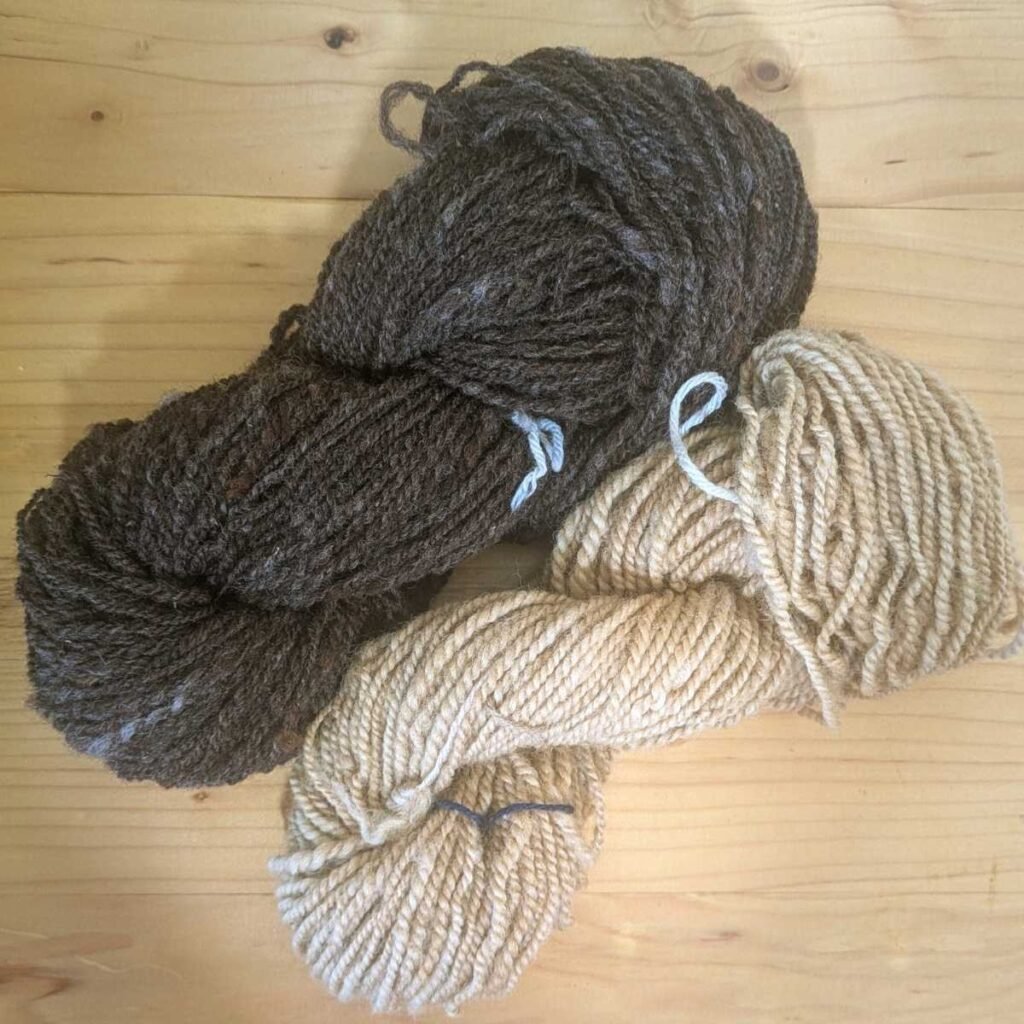 a light brown and dark brown skein of yarn on a wood table