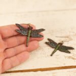 large leather dragonfly earrings held by a hand to show scale