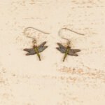 small leather dragonfly earrings displayed on a rustic wooden surface