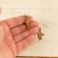 a hand holding small leather hummingbird dangle earrings to show scale