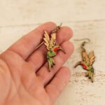 a hand holding leather hummingbird dangle earrings to show scale