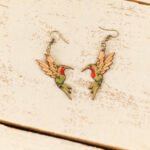 leather hummingbird dangle earrings displayed on a rustic wood surface