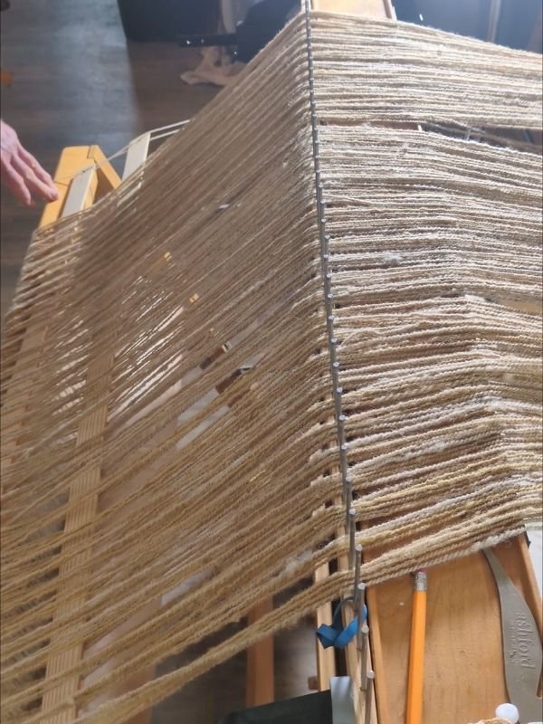 a warp on a loom going over a rattle on the castle of the loom