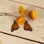 large leather monarch butterfly earrings displayed with strawflowers
