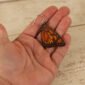 large leather monarch butterfly dangle earring held by a hand to show scale