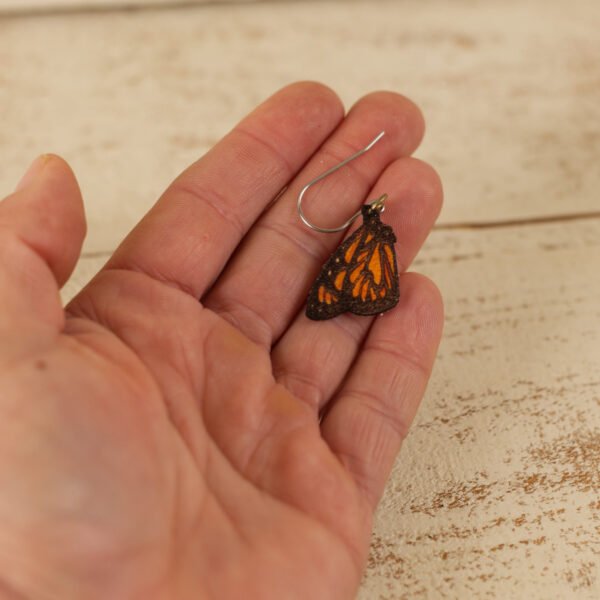 monarch small hand small leather monarch butterfly dangle earrings held by a hand to show scale