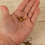 small leather bee dangle held by a hand to show scale