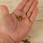 small leather bee dangle held by a hand to show scale