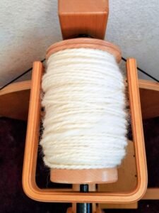 a full bobbin of plyed yard on a louet spinning wheel