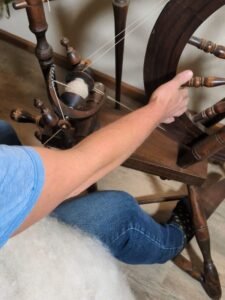 a person spinning on an antique spinning wheel